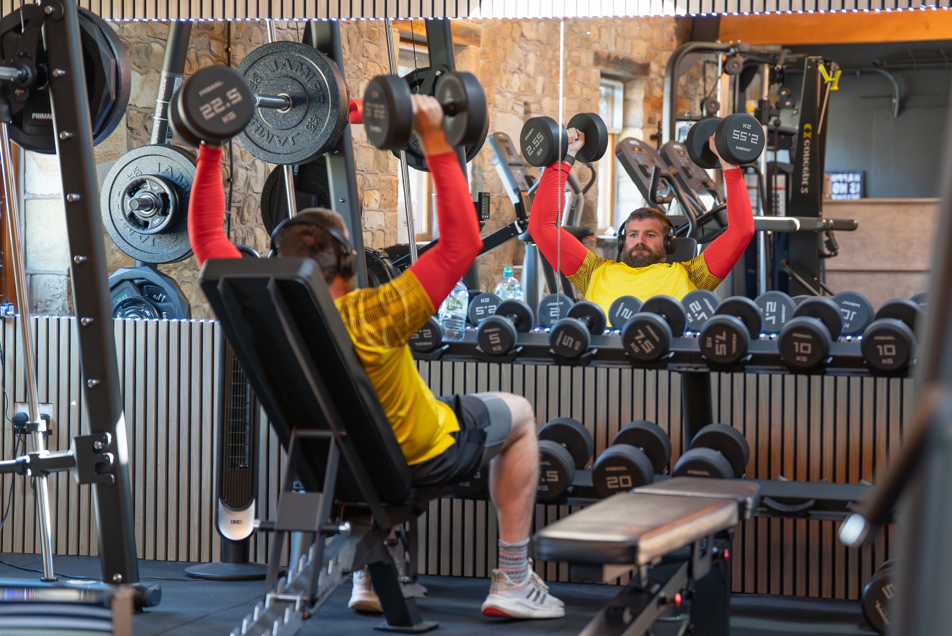 A member pressing dumbbells in the free weights area