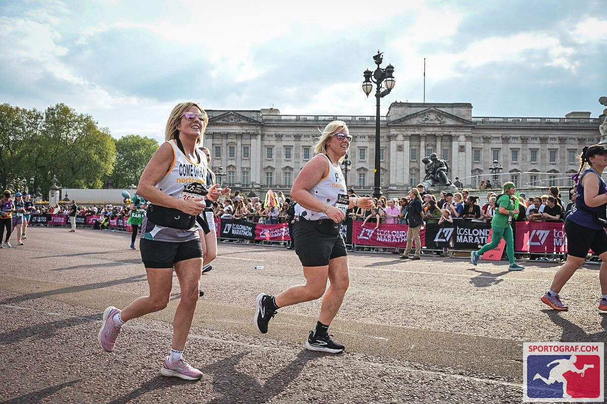 Carrie and Clare running past Buckingham Palace in the London Marathon